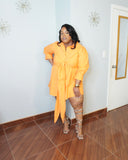 Curvy woman in orange tie front dress angled front view with long sleeves