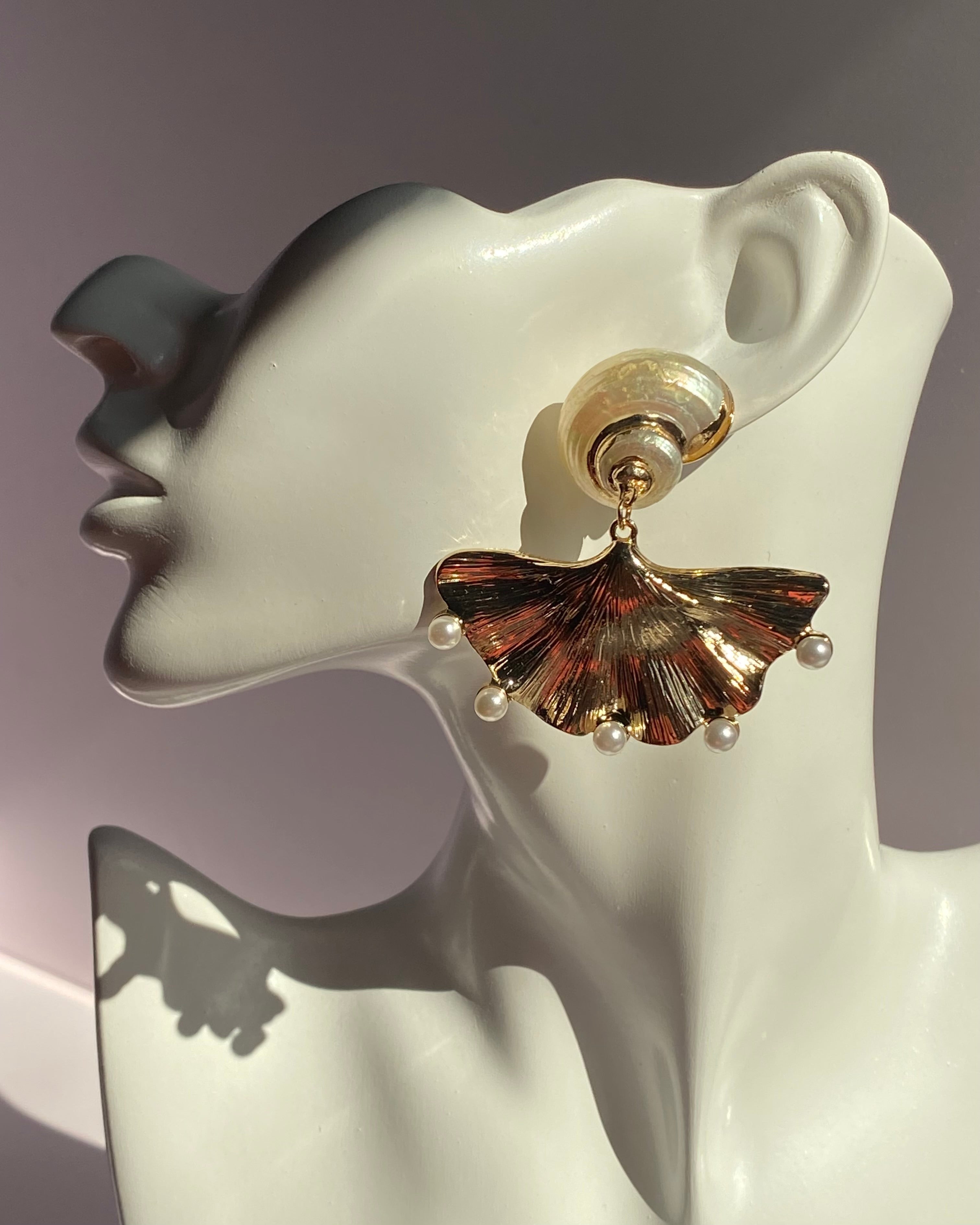 Gold ginkgo leaf fan-shaped statement drop earring with spiral stud and five pearl accents displayed on white mannequin