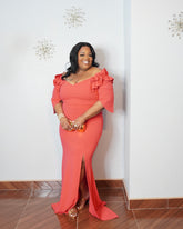Plus size model wearing elegant coral ruffle sleeve evening gown with front slit