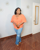 Plus size model styling stretch jeans with orange blouse