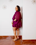 Curvy woman wearing elegant burgundy romper with dramatic sleeves