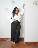 Plus size black pleated wide-leg pants styled with white blouse and statement belt