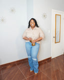 Plus size model wearing high waisted stretch jeans with nude blouse front view