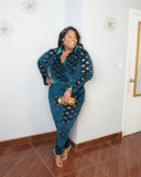 Plus size model smiling in emerald mesh bodysuit and pants set styled with gold clutch and heels