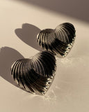 Silver sculpted heart statement earrings with ribbed metallic texture