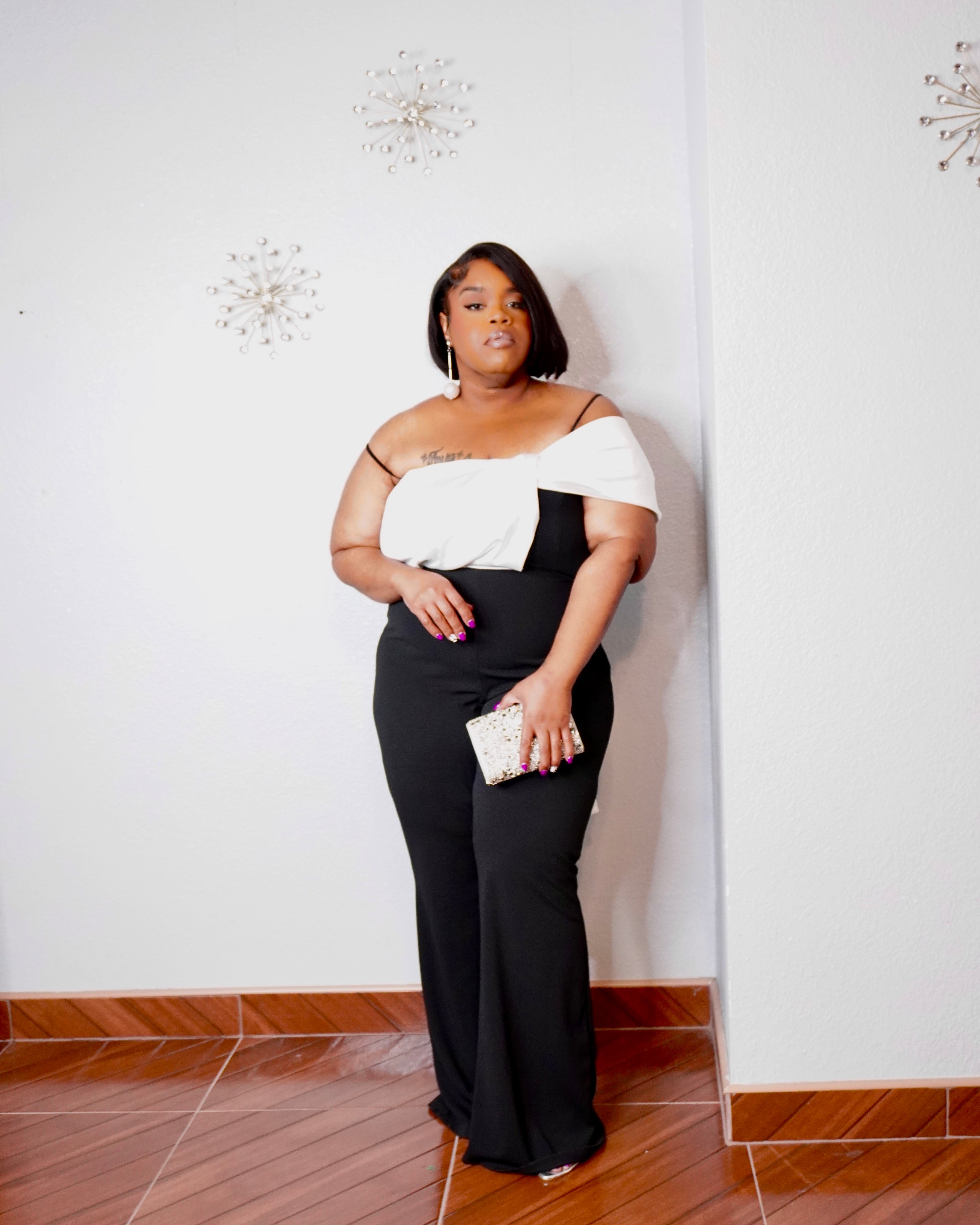 Elegant black and white plus-size formal jumpsuit featuring a draped neckline and fitted waist.