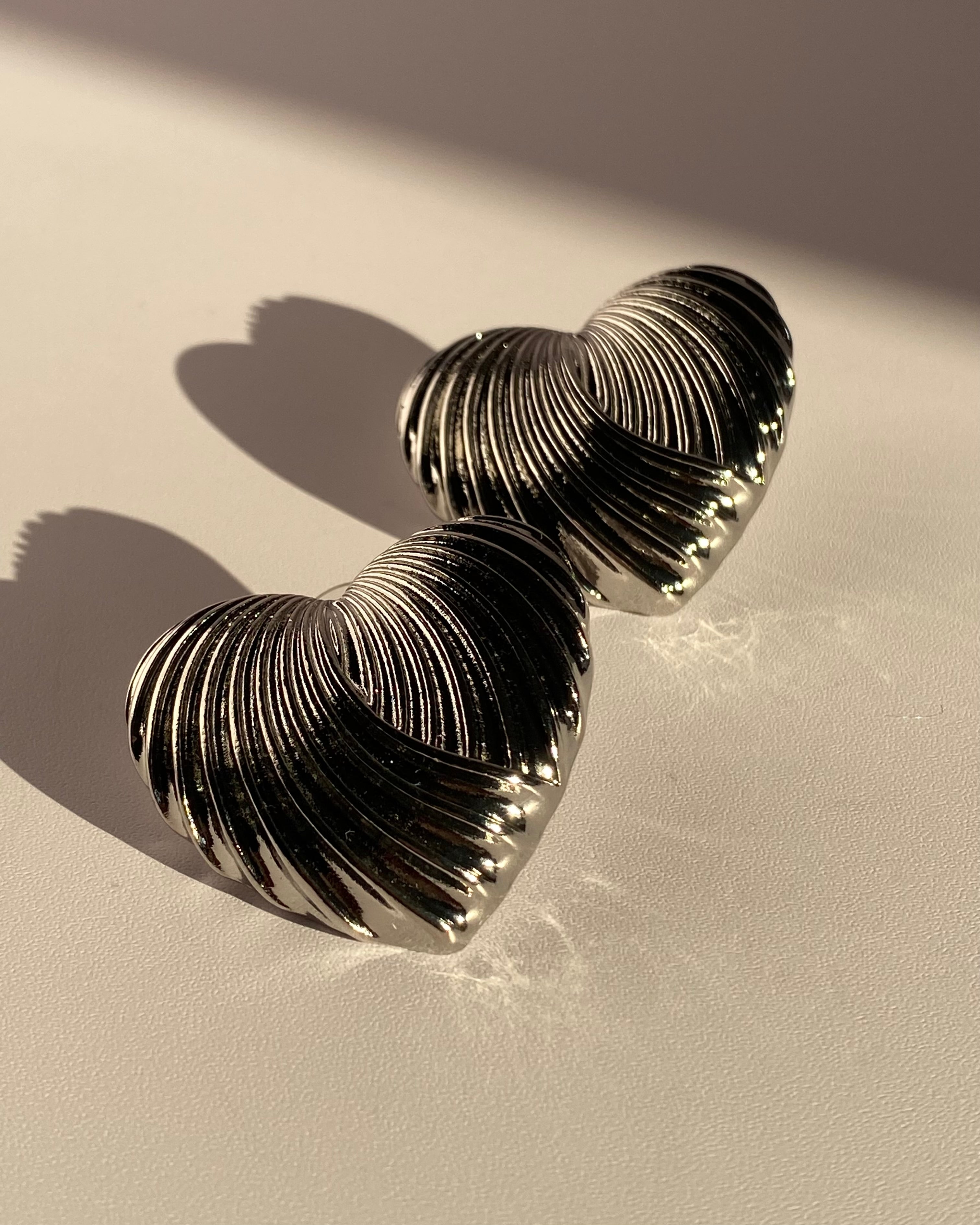 Silver sculpted heart statement earrings with ribbed metallic texture