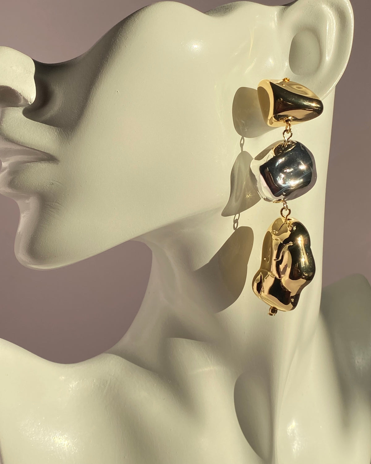 Gold and silver mixed metal abstract drop statement earring displayed on jewelry bust