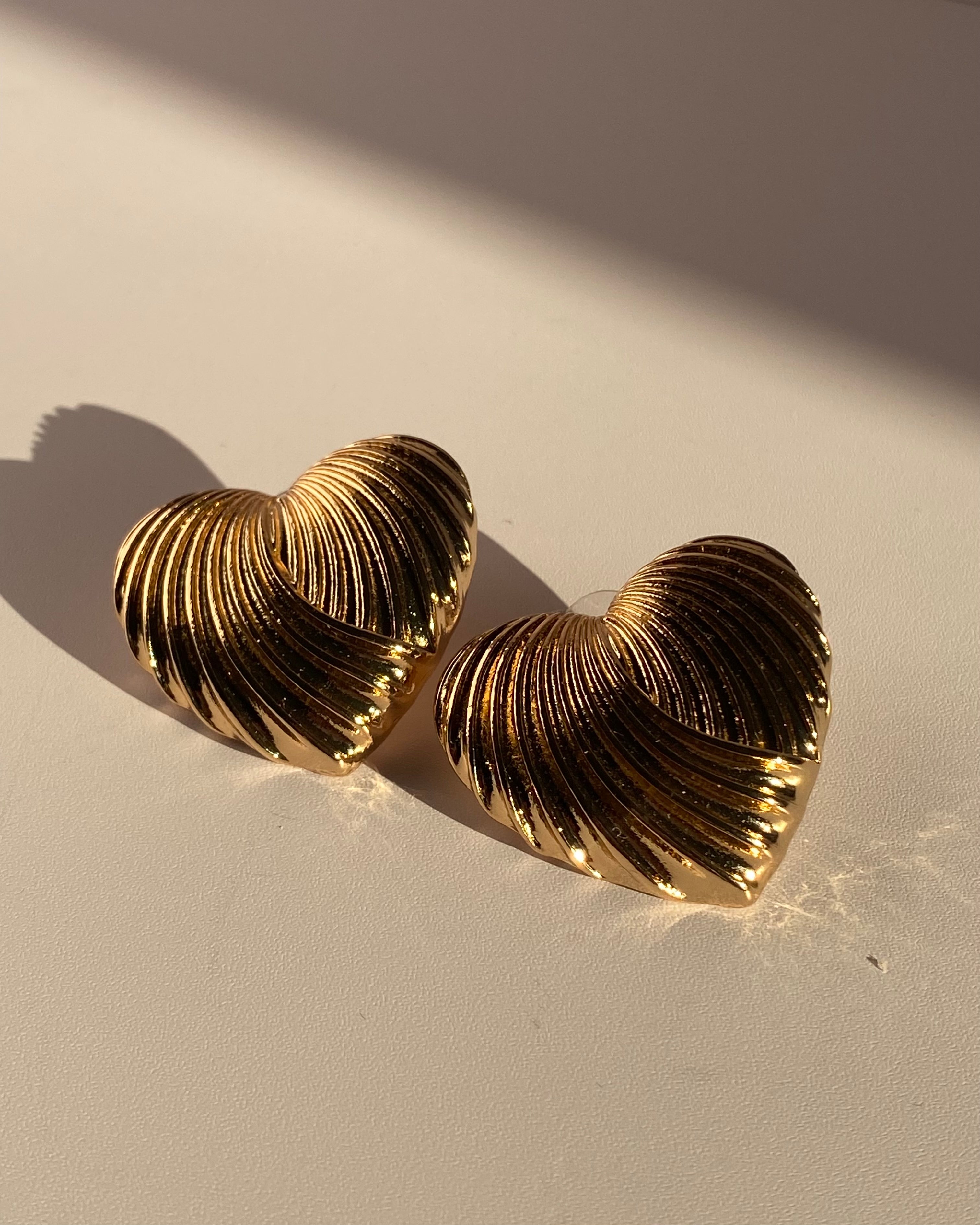 Gold sculpted heart statement earrings with ribbed metallic texture