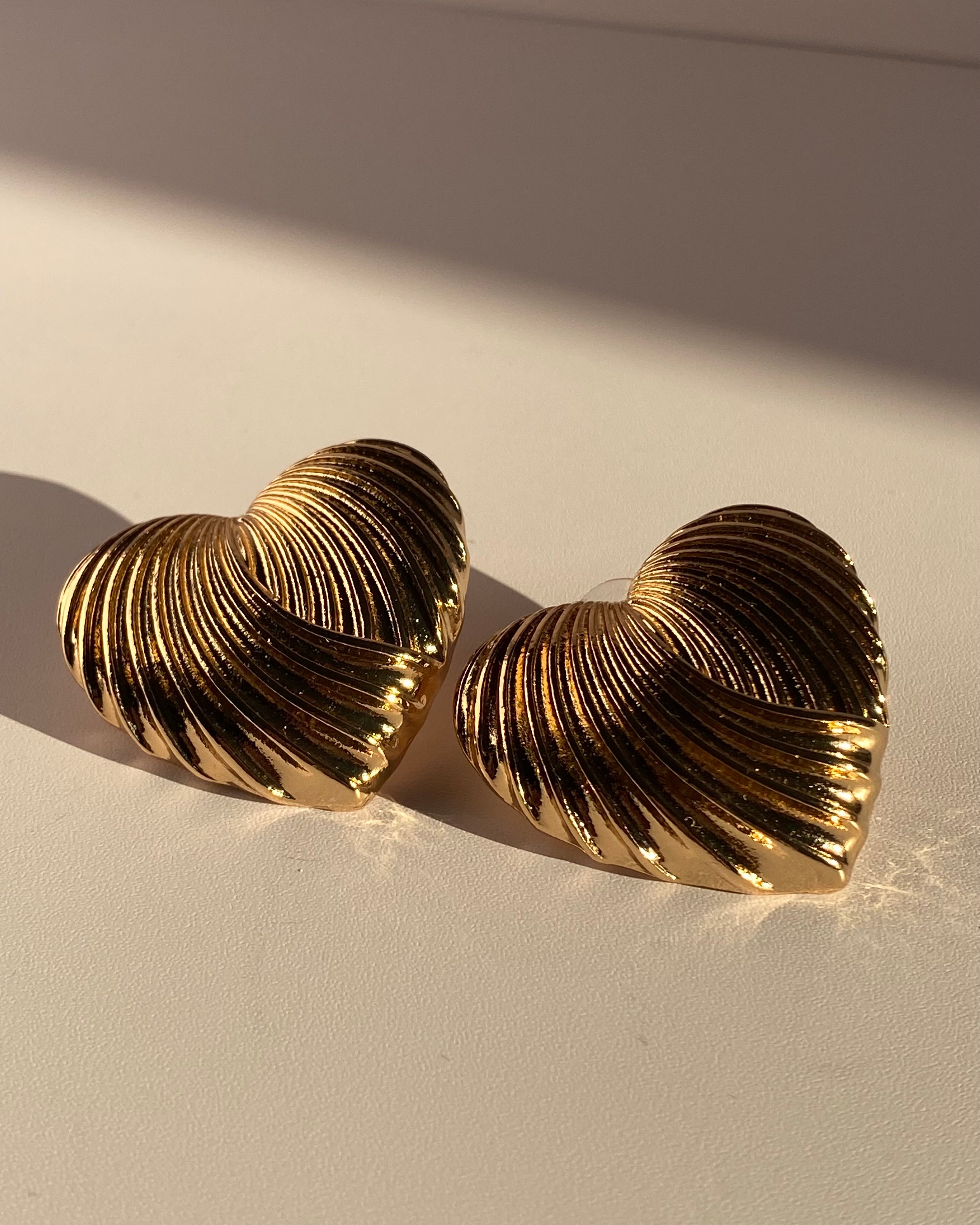 Gold sculpted heart statement earrings with ribbed metallic texture