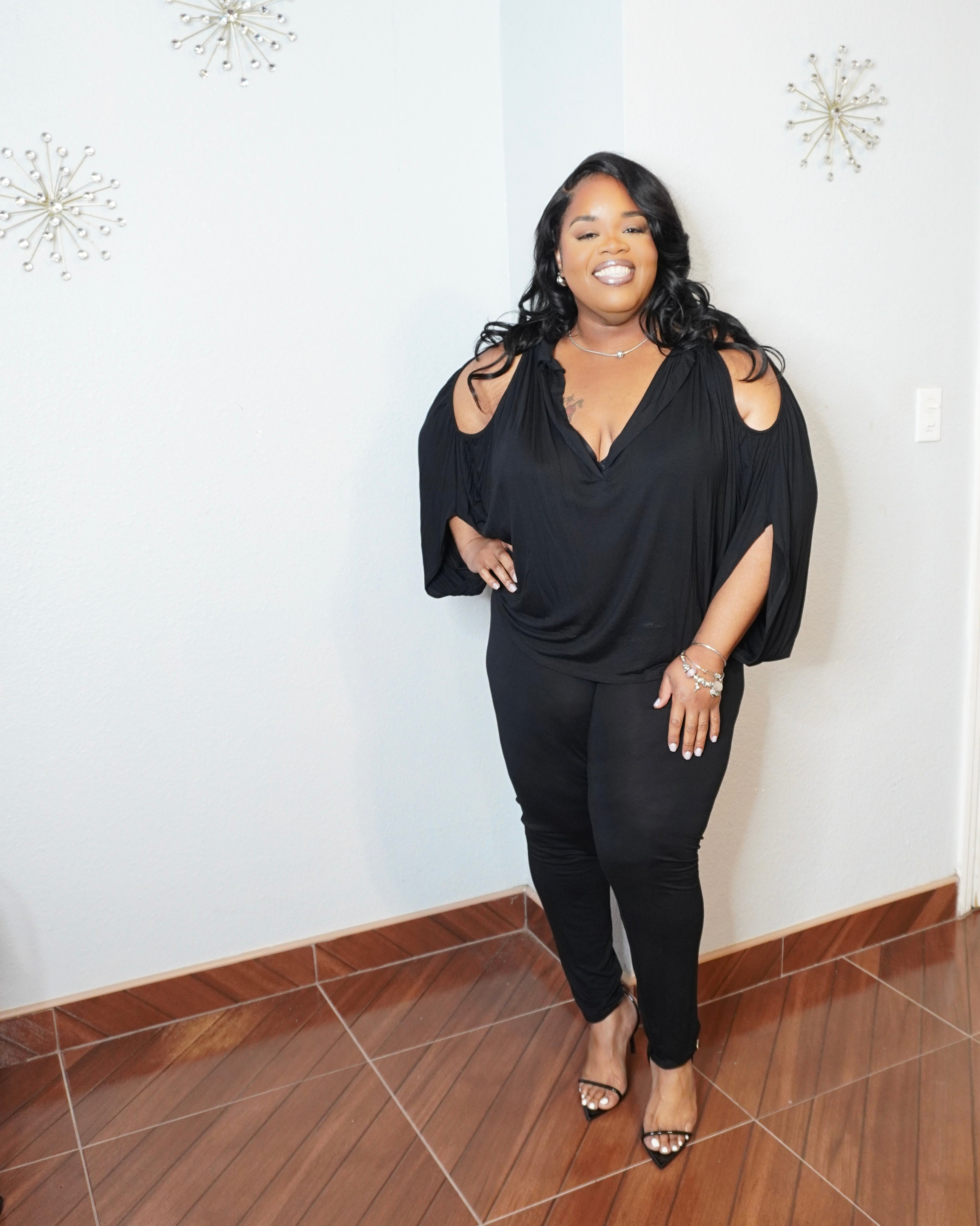 Plus size model posing in cold shoulder batwing set with heels