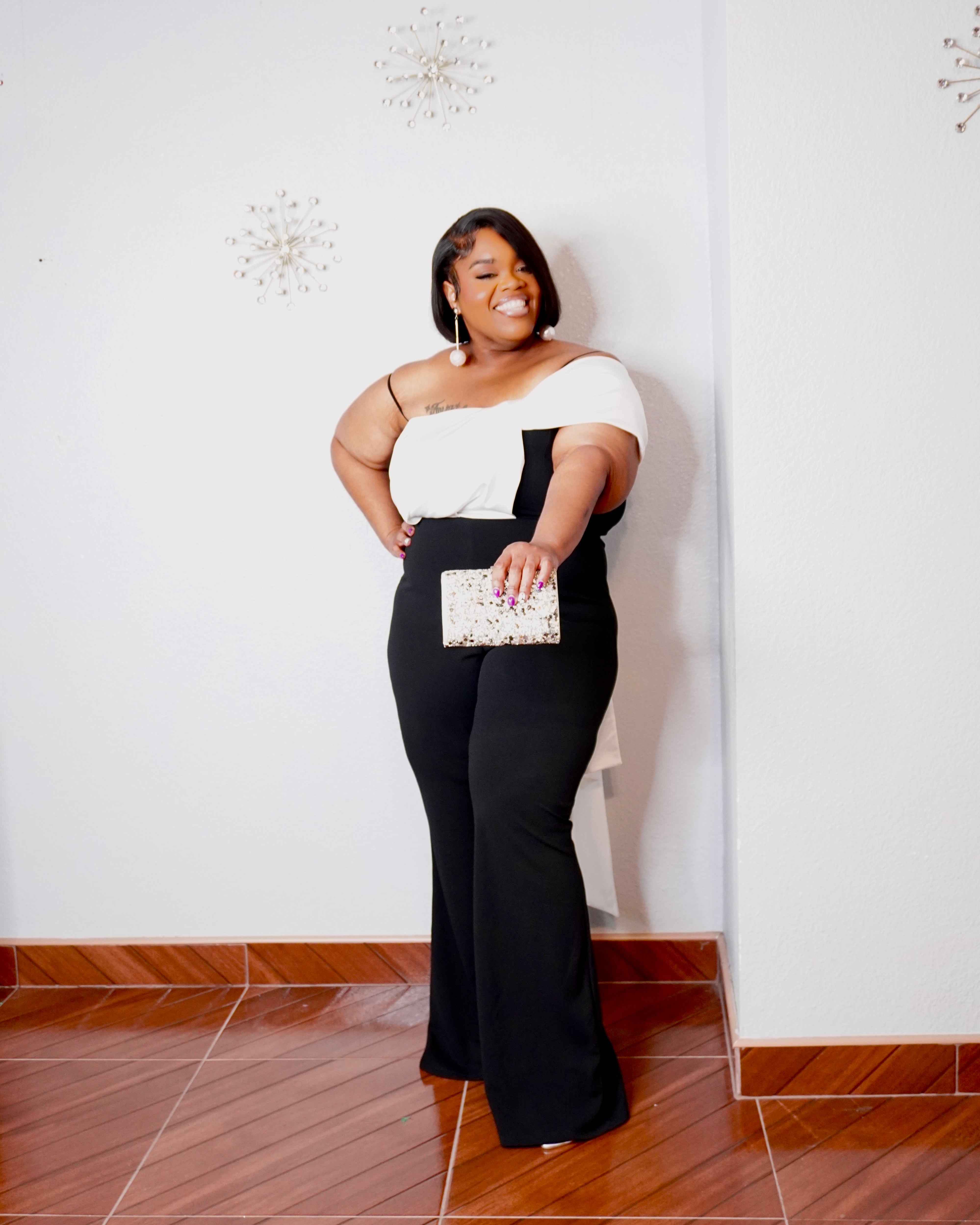 Plus-size woman wearing LYSAIRE black and white asymmetrical draped jumpsuit with wide-leg pants.