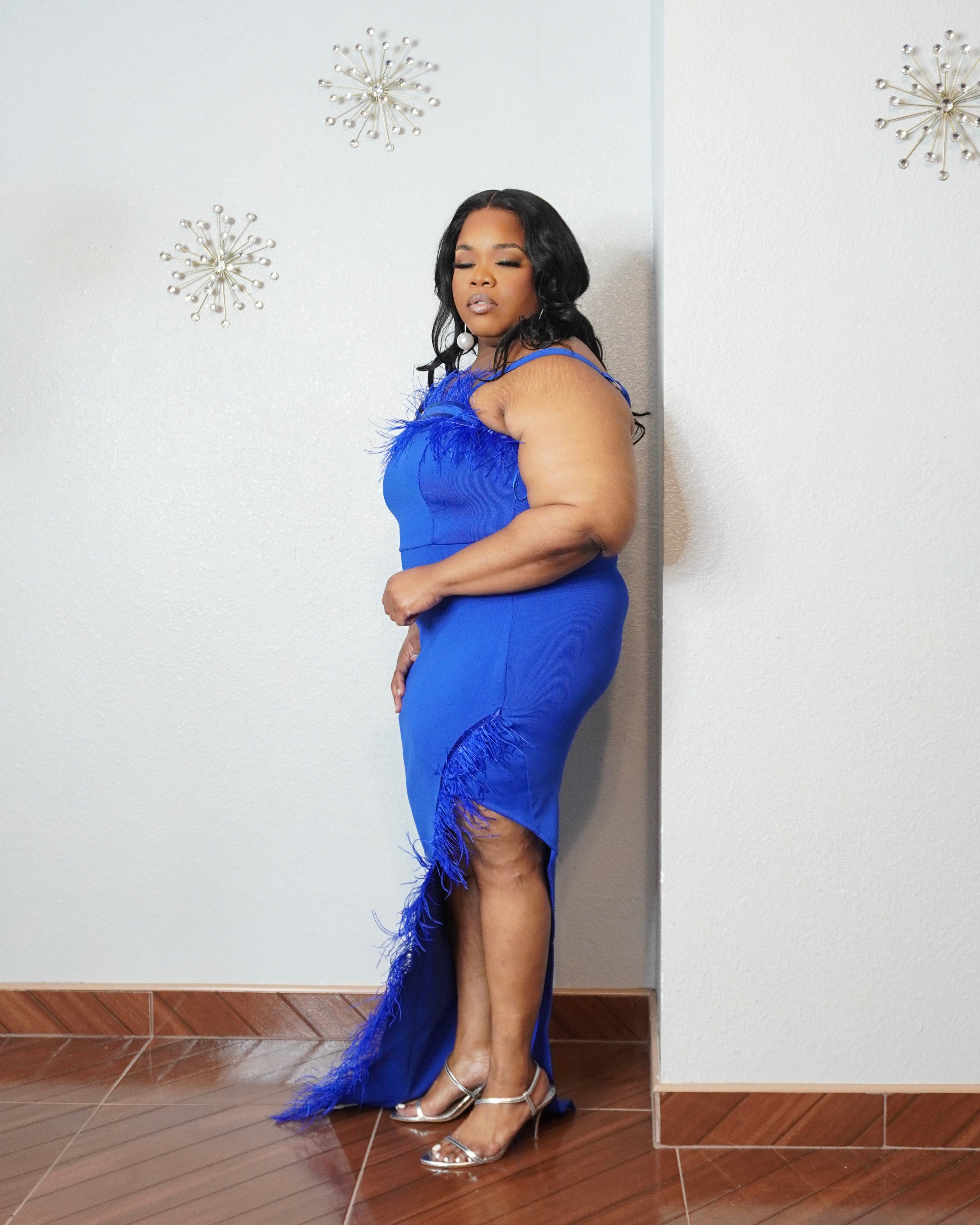 Curvy woman modeling elegant royal blue bodycon dress with feather trim neckline