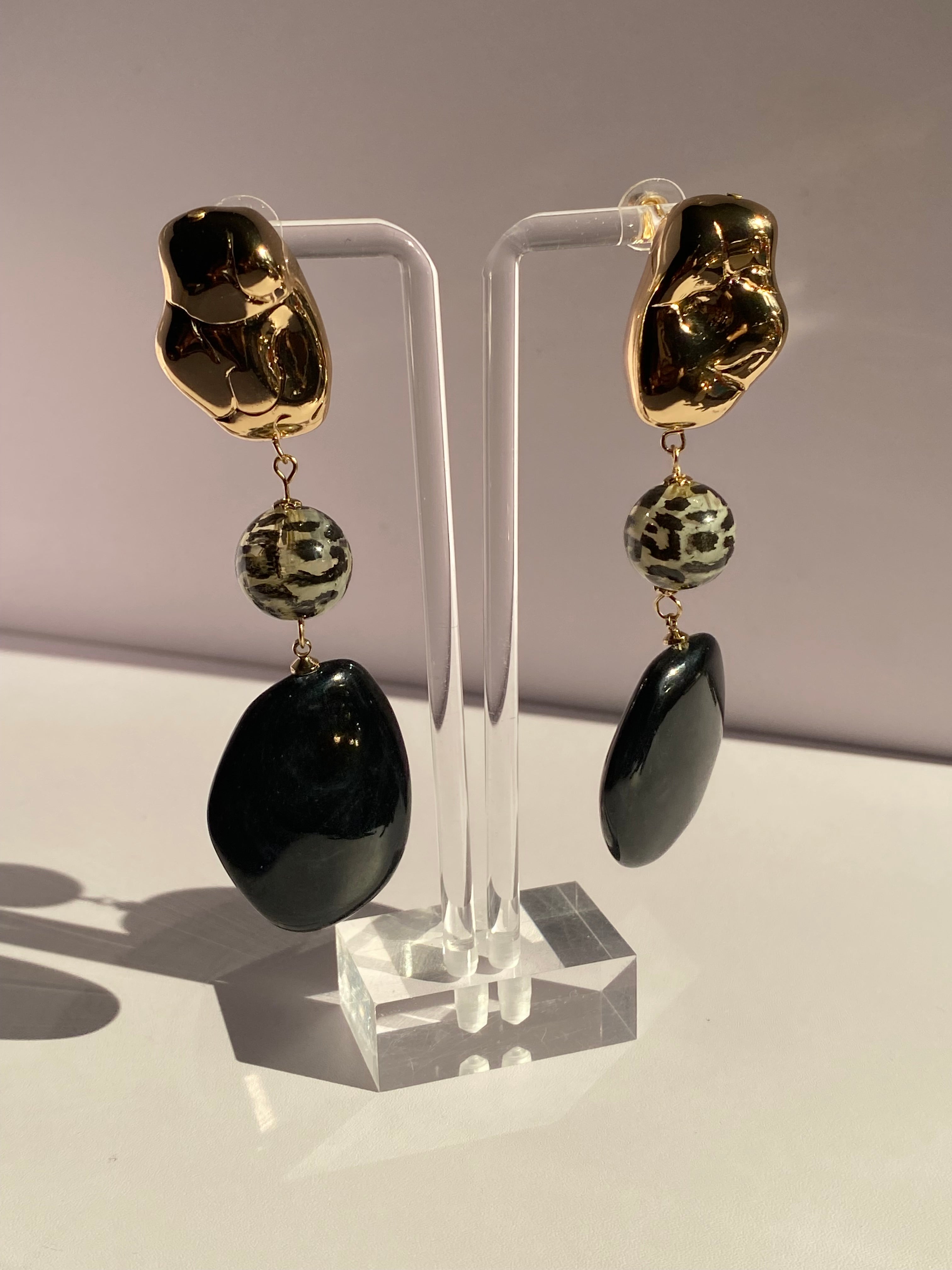 Black and gold leopard bead statement earrings featuring a three-part drop design with polished black oval pendants